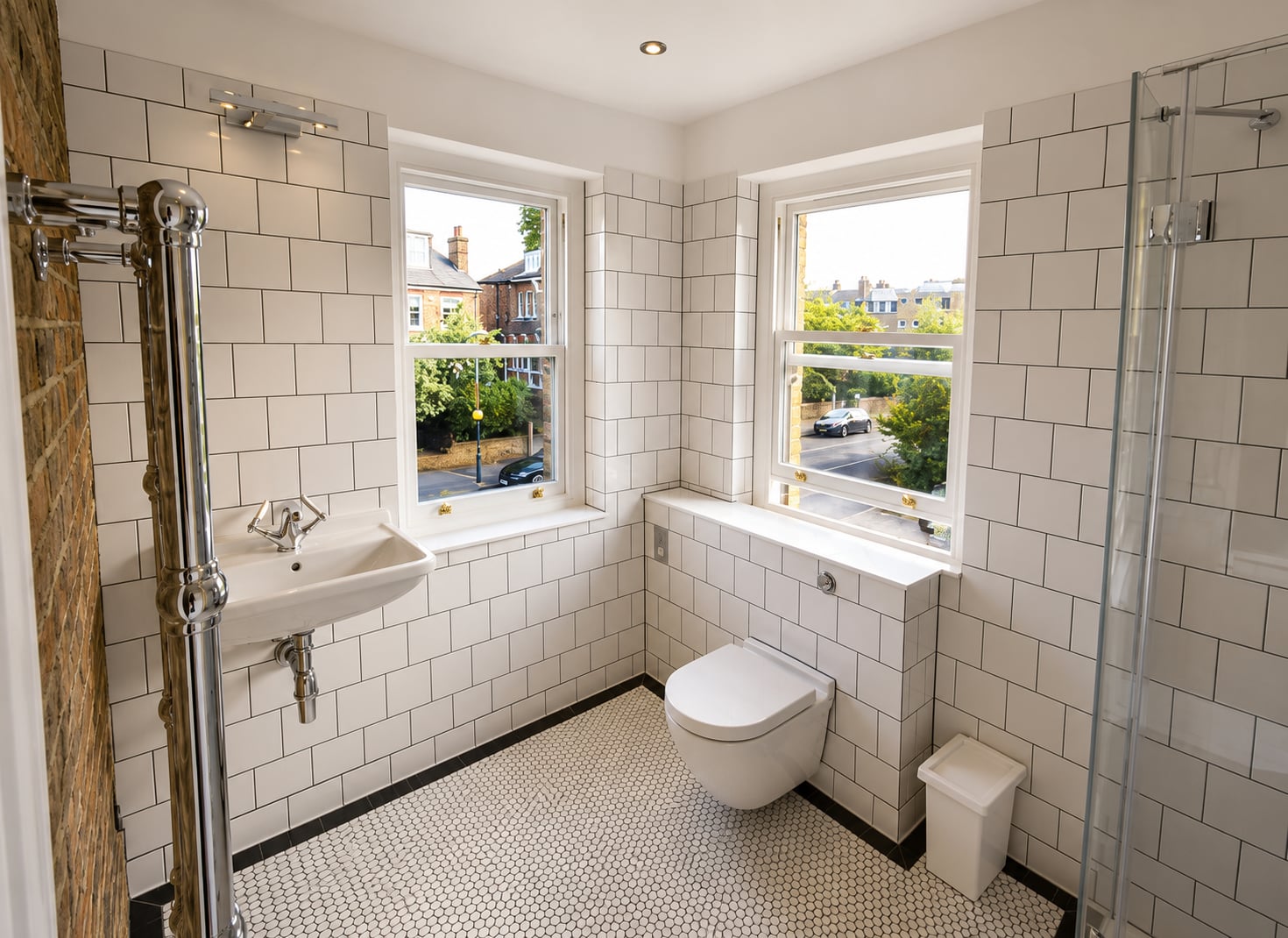 Two white timber sash windows in a white tiled bathroom overlooking a suburban street