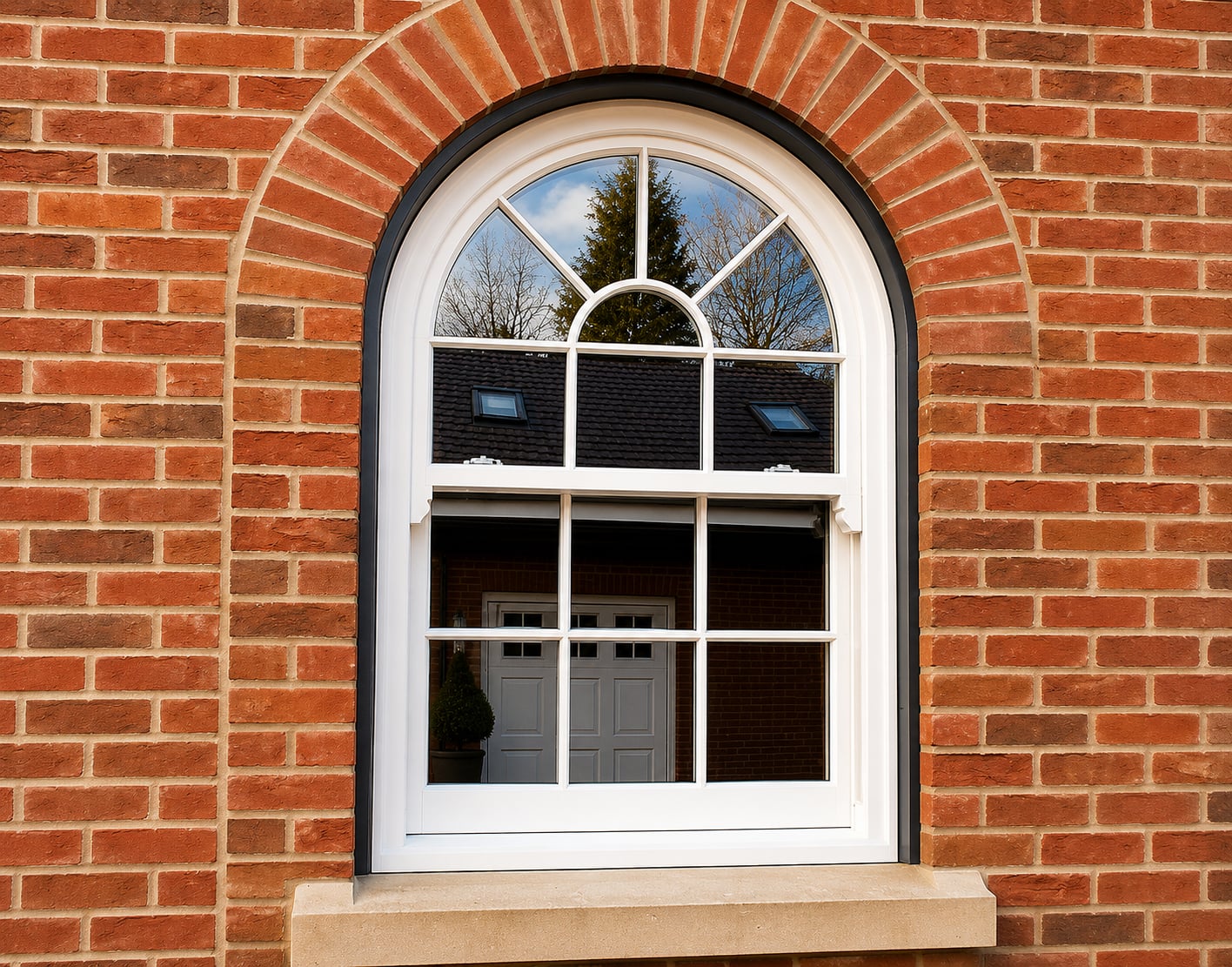 Arched white timber sash window with radial glazing bars set in a red brick arch