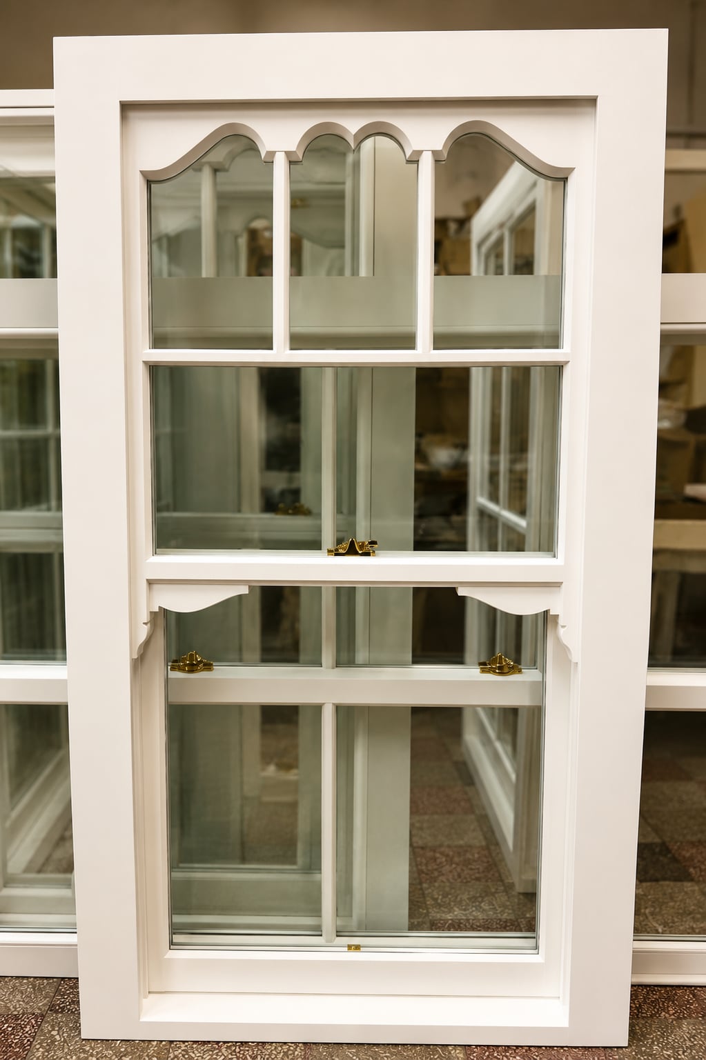 White timber sash window with Gothic arched glazing bars and brass fasteners, photographed in the workshop