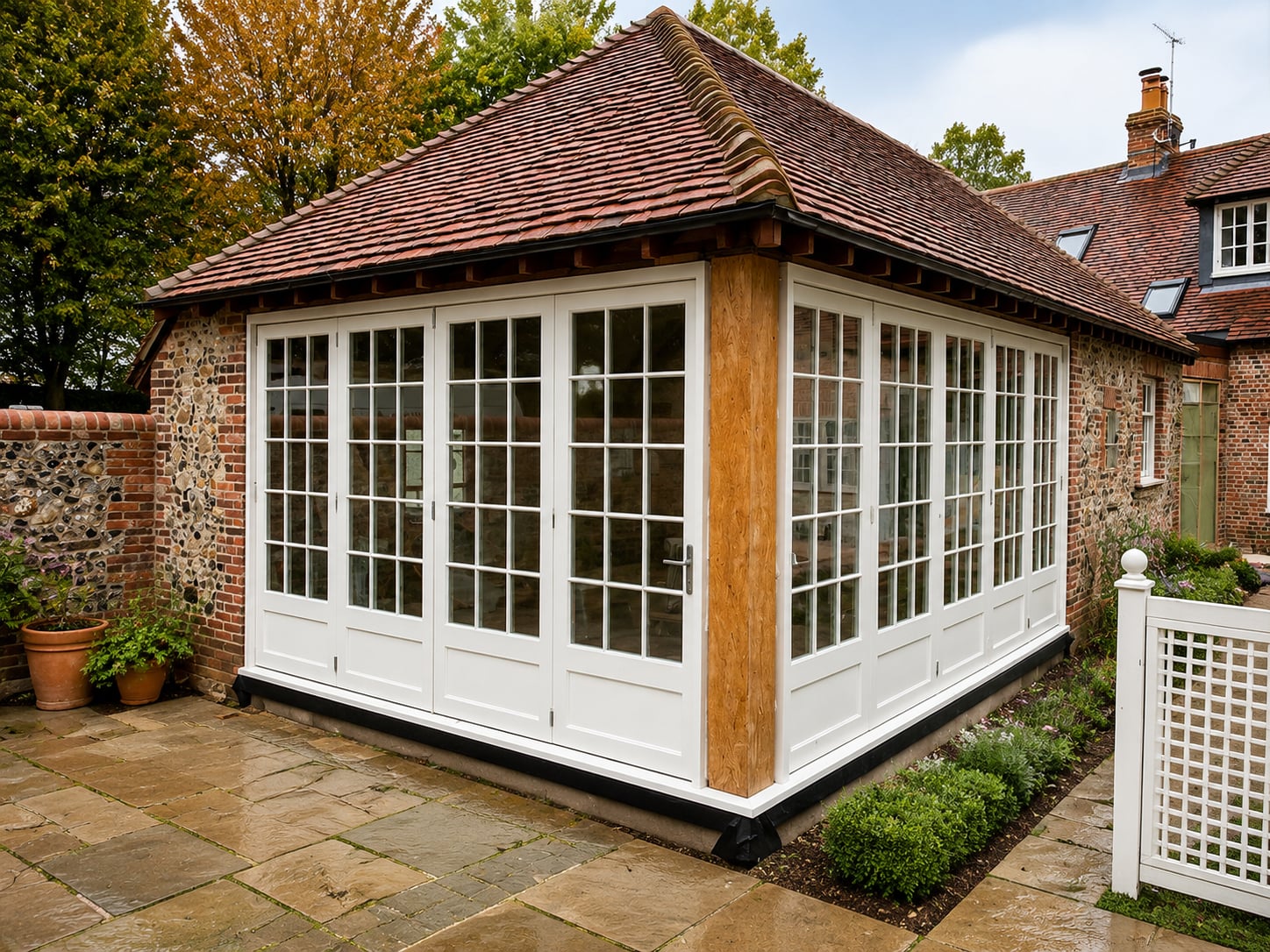 White timber orangery glazing with French doors and fixed lights on a tiled garden room