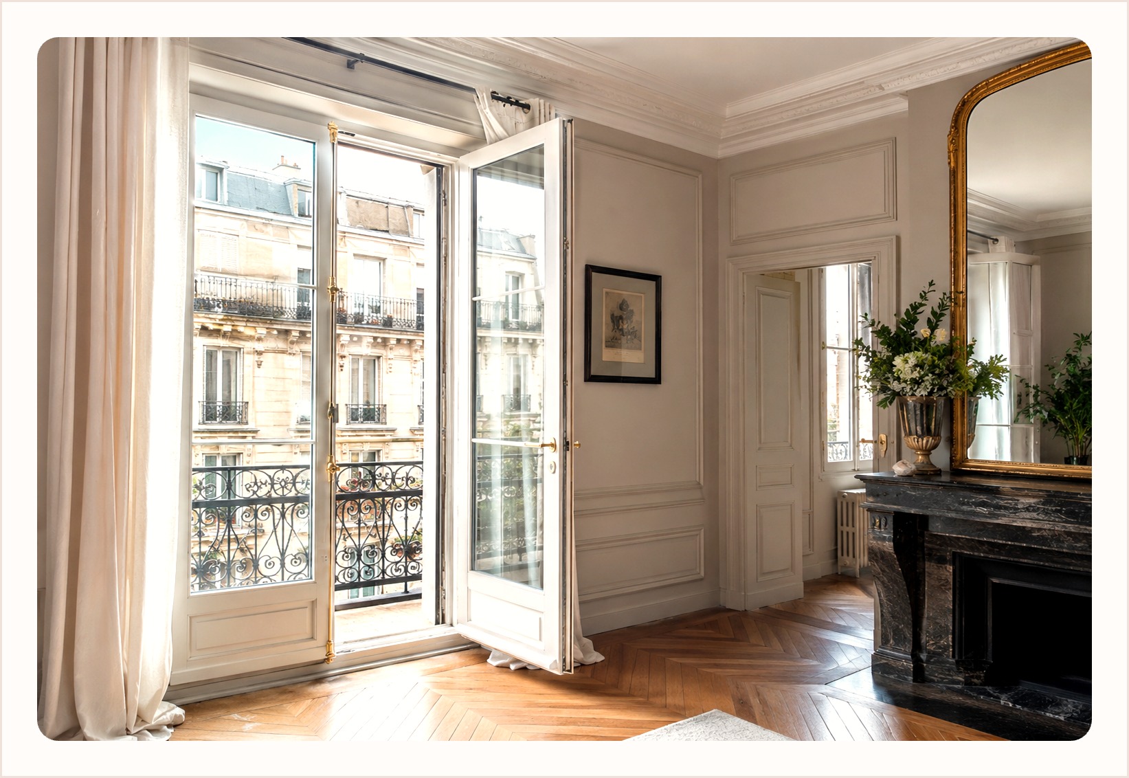 Open white timber French doors leading to a balcony in a panelled room with a marble fireplace