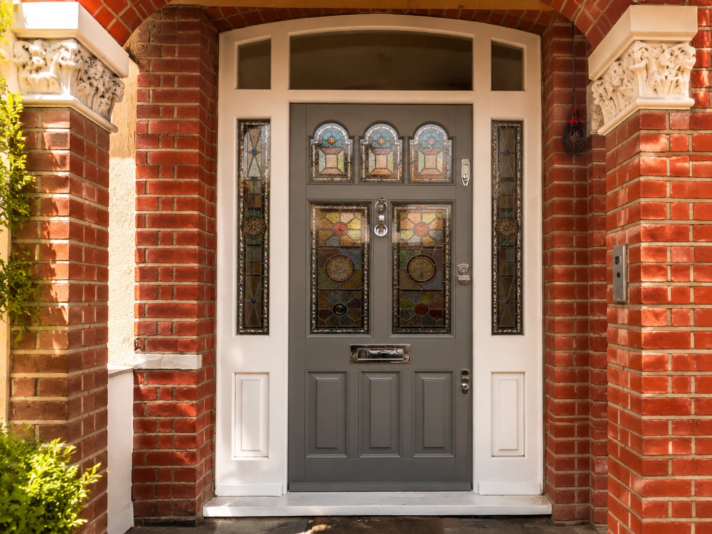 Grey timber door with stained glass panels, side lights and a three panel top light