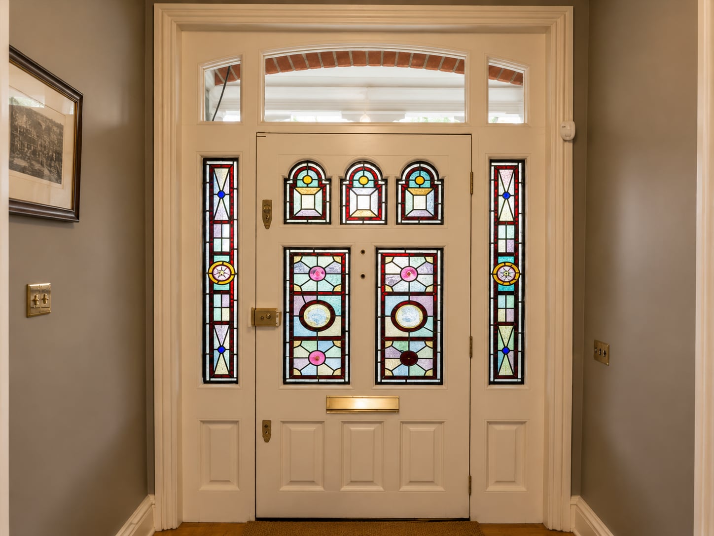 Cream timber door with colourful stained glass panels and side lights, seen from the hallway
