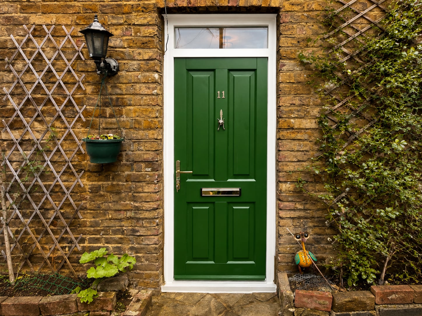 Green panelled timber door with a brass letter plate set in a stock brick opening