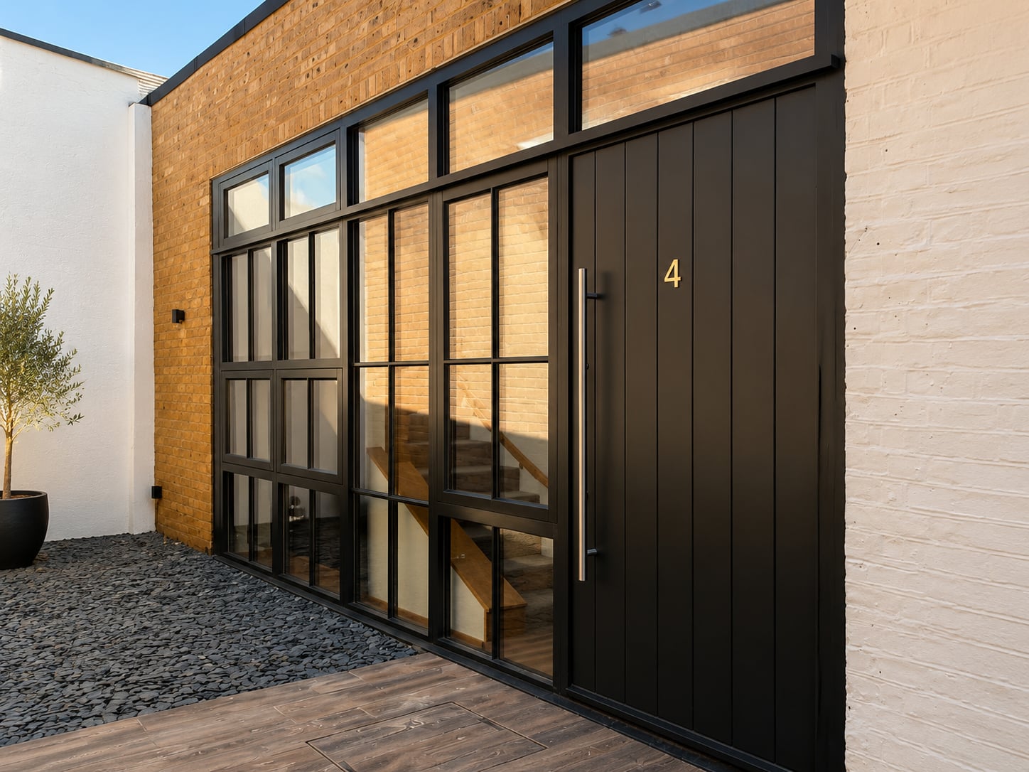Contemporary dark timber door with vertical boarding beside a full height glazed screen